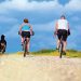 Man and woman riding bikes with dog running beside them