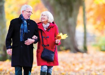 Elderly couple walking through fall leaves