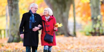 Elderly couple walking through fall leaves