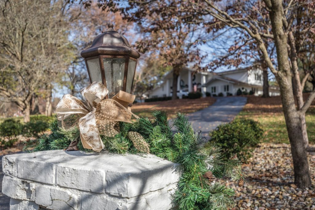 Exterior lamp decorated for Christmas with house in background