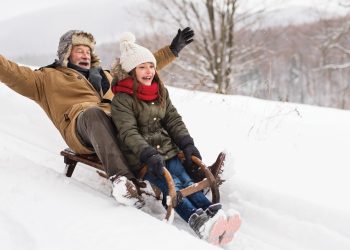 Grandfather and granddaughter sledding down hill