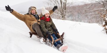 Grandfather and granddaughter sledding down hill