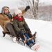 Grandfather and granddaughter sledding down hill