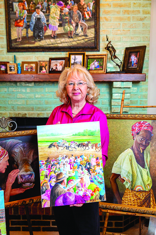 Artist Rhonda McEnroe holding a race horse painting