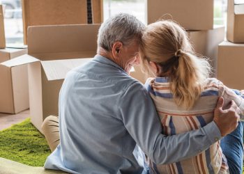 happy senior couple sitting on the floor with moving boxes