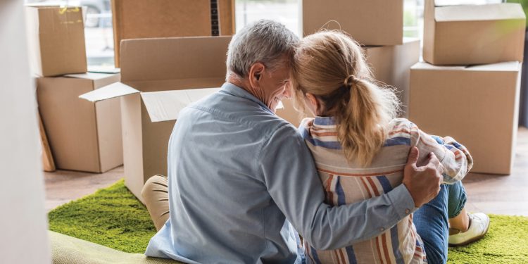 happy senior couple sitting on the floor with moving boxes