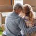 happy senior couple sitting on the floor with moving boxes