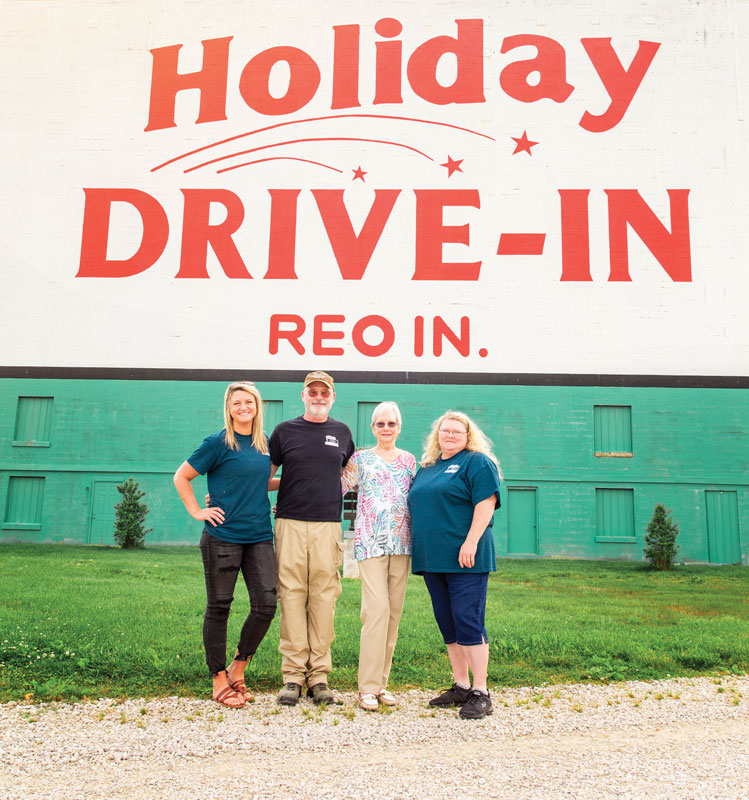 The Moseley family happily poses in front of the Holiday Drive-In sign.