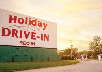 The Holiday Drive-In sign stands tall in front of the setting sun.