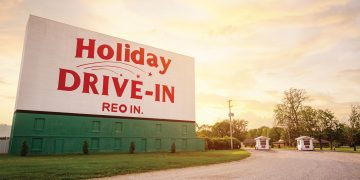 The Holiday Drive-In sign stands tall in front of the setting sun.