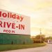 The Holiday Drive-In sign stands tall in front of the setting sun.