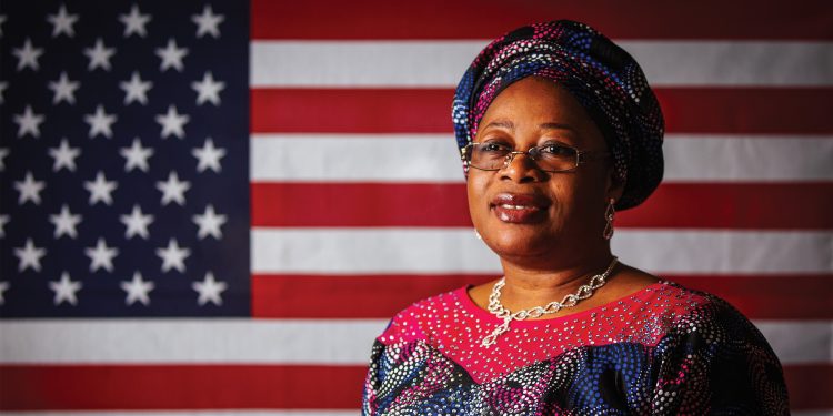 Atinuke Wilhite smiles in front of an American flag.