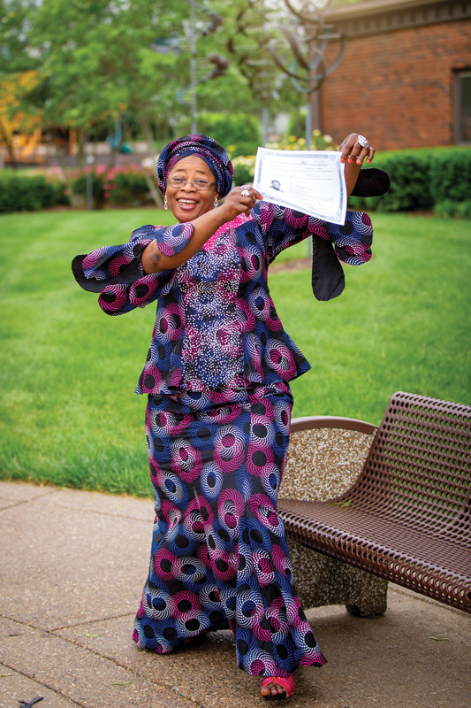 Atinuke Wilhite dances with joy as she shows off her certificate declaring permanent residency.