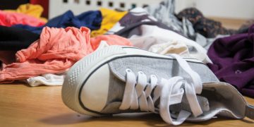 A children's sneaker lying among a pile of dirty laundry.