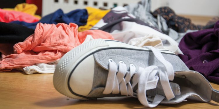 A children's sneaker lying among a pile of dirty laundry.
