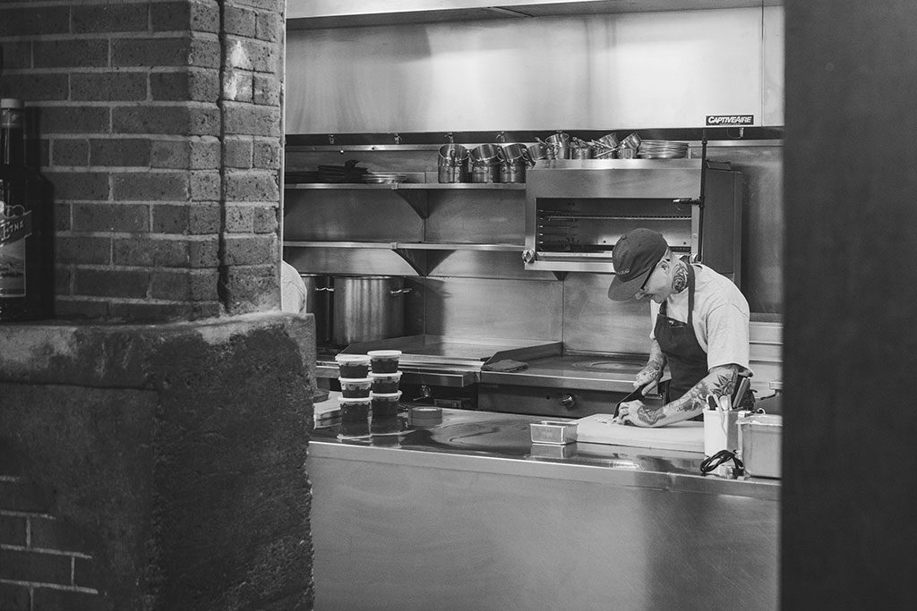 Bolton smiles as he works hard in the kitchen to prepare a dish.