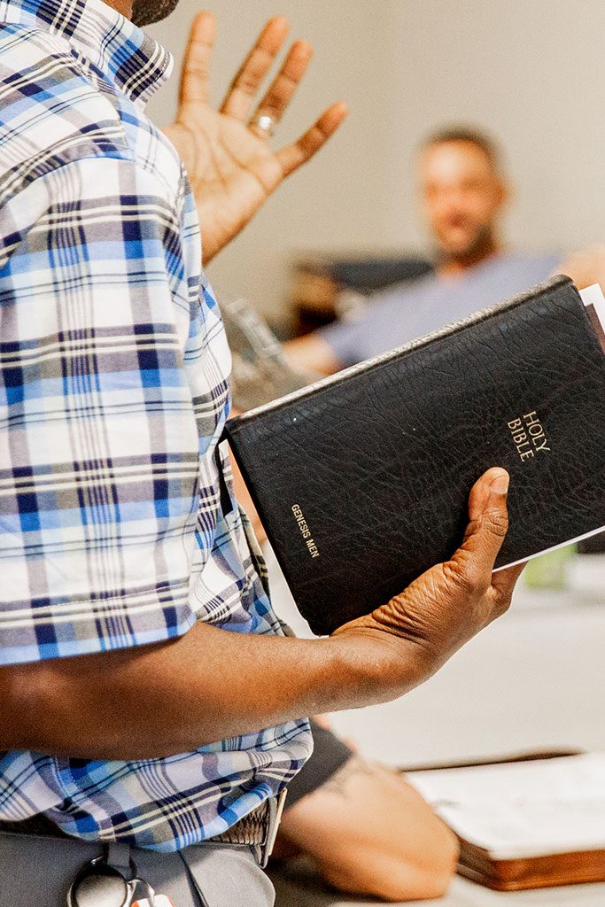 "Brother G" holds a bible as he talks to the individuals in the program.