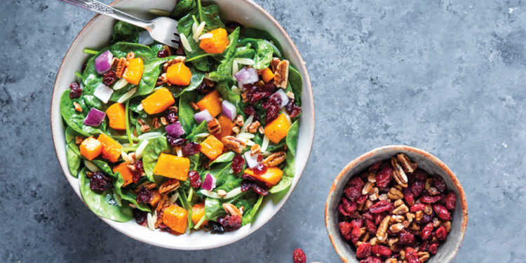 Overhead photo of autumn squash salad with side of walnuts and cranberries