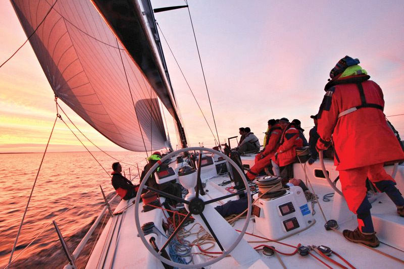 Sailing team on sailboat during sunset