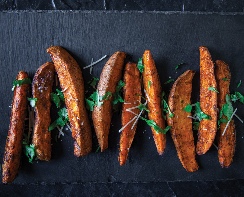 Overhead photo of sweet potato wedges on dark background